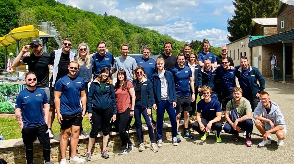 Groepsfoto van het Stuurlui-team tijdens een Alle hens aan dek Dag in een groene, heuvelachtige omgeving, met een mix van collega’s die lachend poseren voor de camera